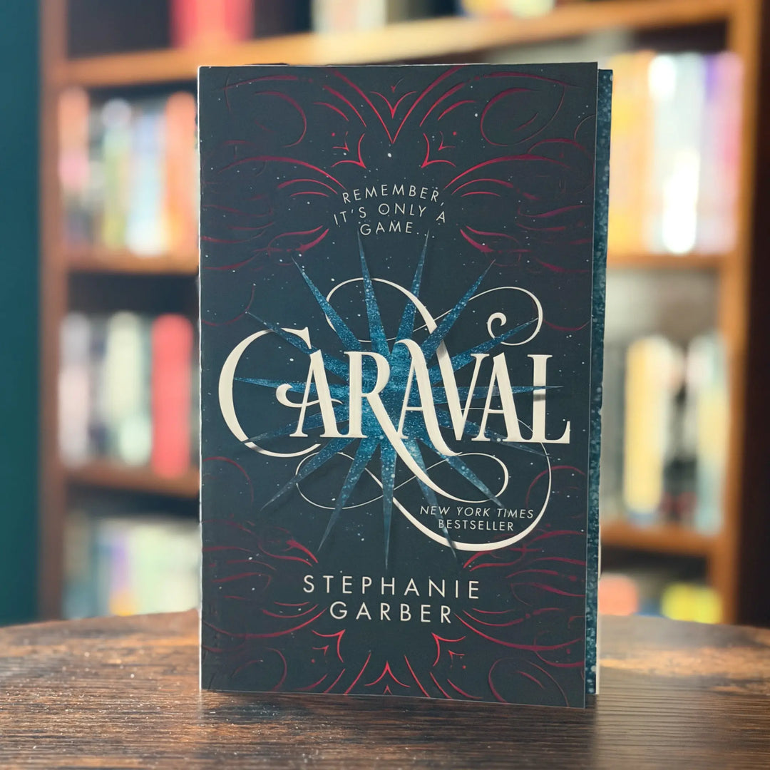 Book titled 'Caraval' by Stephanie Garber on a wooden surface with a blurred bookshelf background.