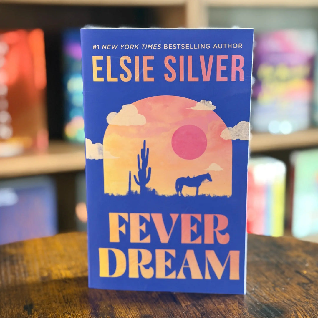 Book titled 'Fever Dream' by Elsie Silver on a wooden surface with a blurred bookshelf background.