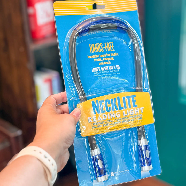 Hand holding a necklite reading light in its packaging