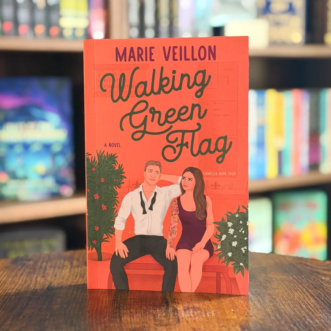 Book cover of 'Walking Green Flag' by Marie Veillon on a wooden surface with a blurred bookshelf background.