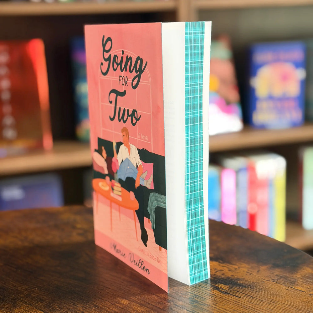 Book titled 'Going for Two' on a wooden surface with a blurred bookshelf background