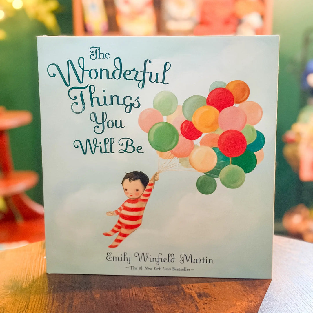 Book titled 'The Wonderful Things You Will Be' with colorful balloons and a child illustration on a wooden surface.