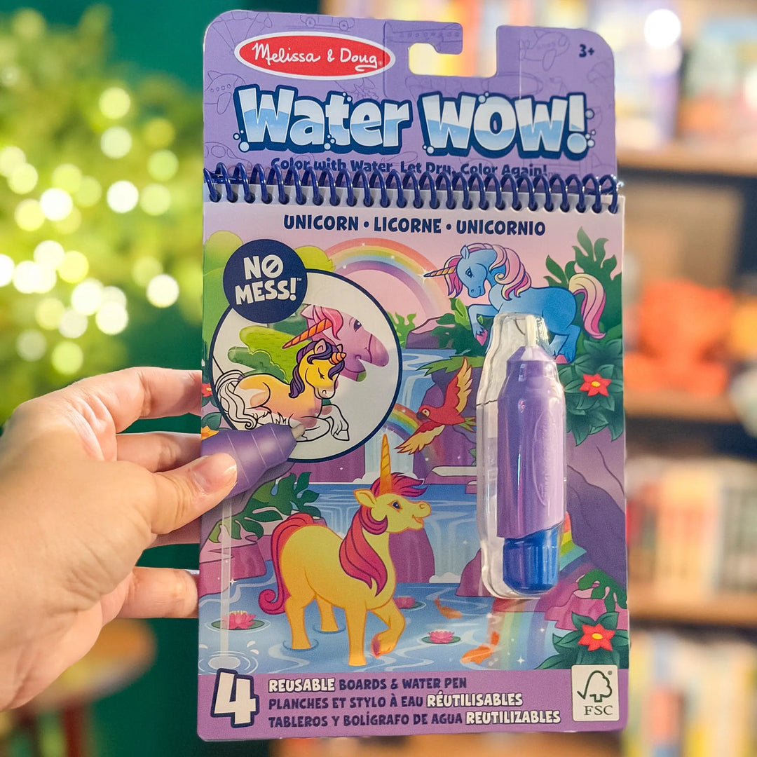Melissa & Doug Water Wow! unicorn coloring book with water pen held by a hand against a blurred background.