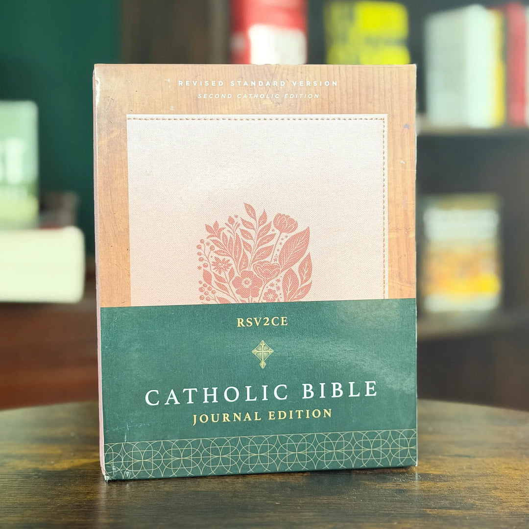 Catholic Bible Journal Edition book standing upright on a wooden table, with a green and beige cover design and floral illustration.