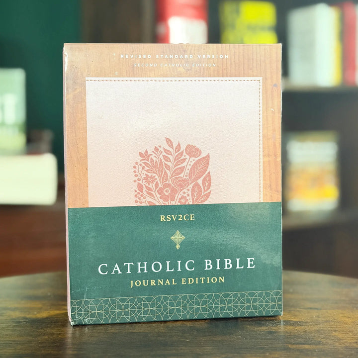 Catholic Bible Journal Edition book standing upright on a wooden table, with a green and beige cover design and floral illustration.