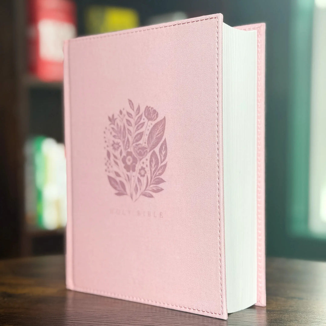 A pink cloth Bible book cover with a floral leaf emblem and the words &