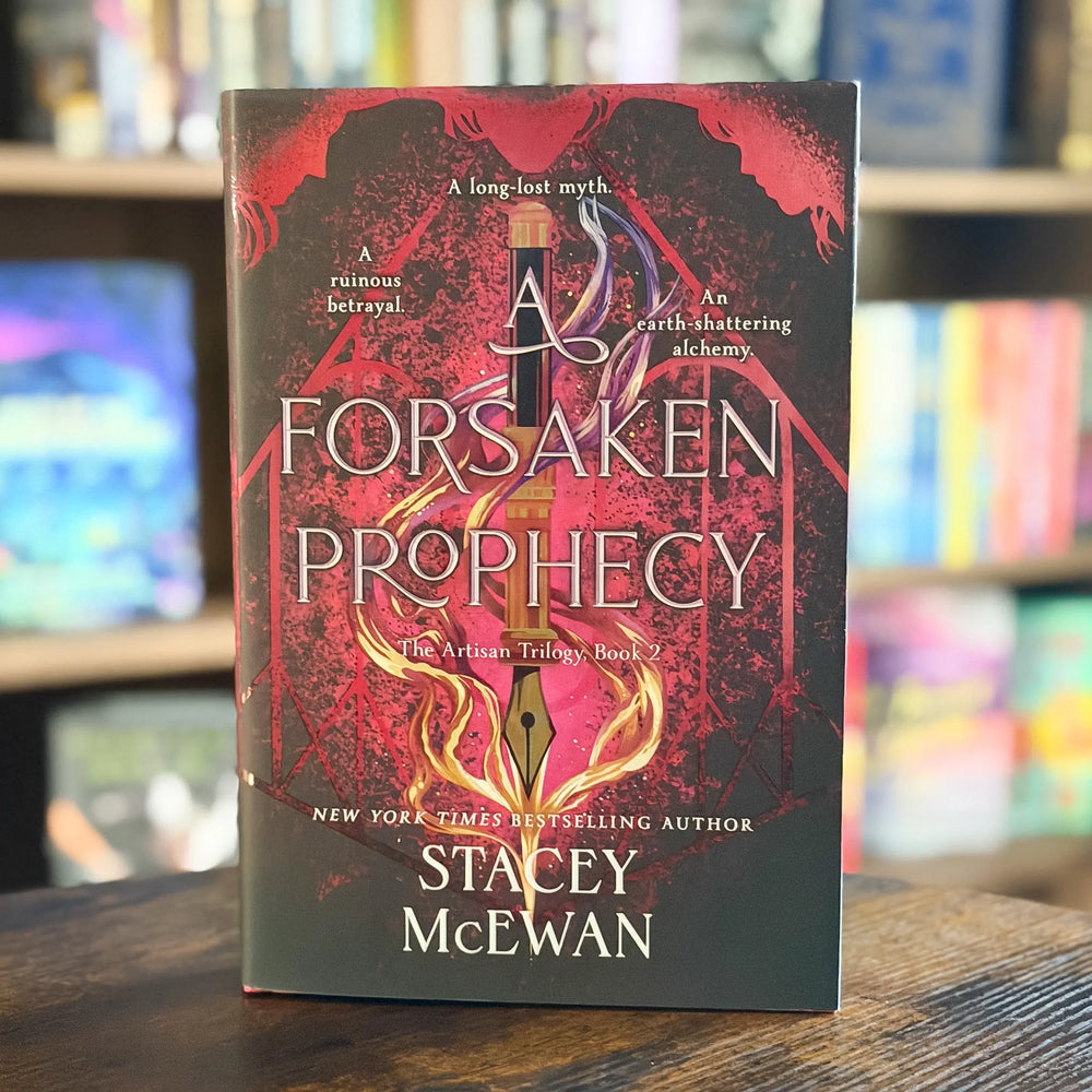 The book 'A Forsaken Prophecy' by Stacey McEwan stands upright on a wooden table with a blurred bookshelf background.