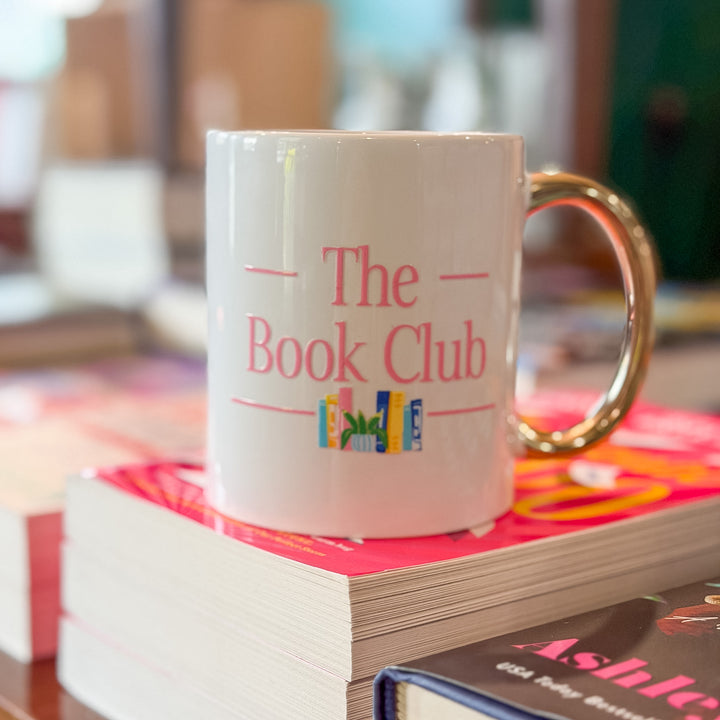 A white ceramic mug with a gold handle, printed with &