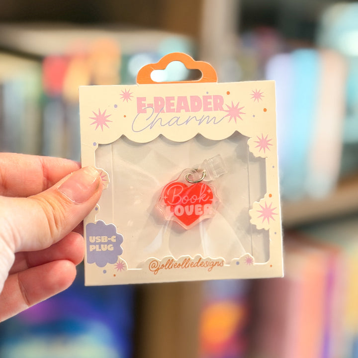 A hand holds a packaged red heart-shaped USB-C charm with the words &