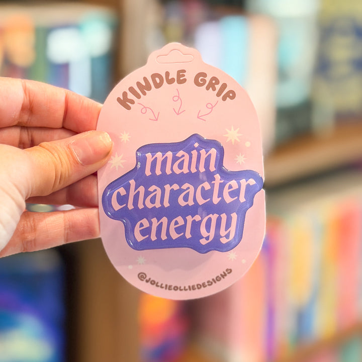 A hand holds a pink novelty Kindle grip tag with the text &