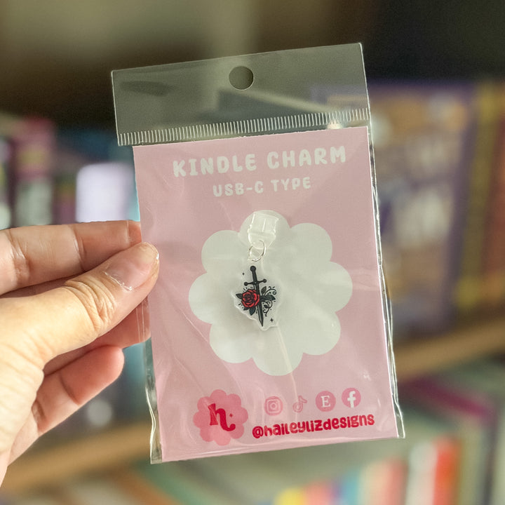 A hand holds a clear plastic blister pack containing a small charm. The card says &