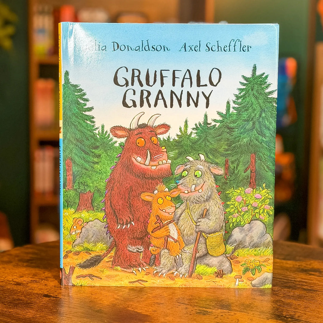 Gruffalo Granny book by Axel Scheffler and Julia Donaldson, standing upright on a wooden table with a blurred library or bookstore background.