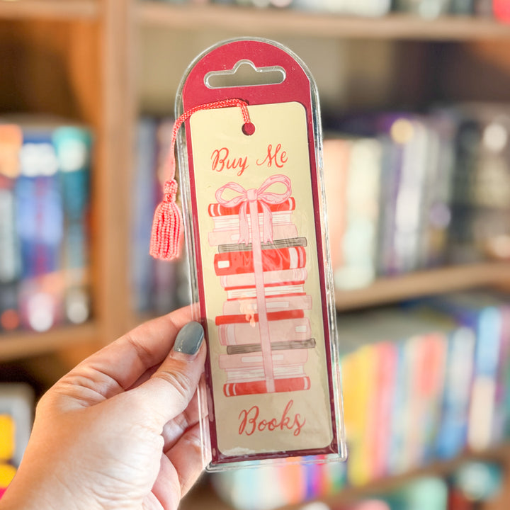 A rectangular bookmark with a tassel, featuring an illustration of a stack of books tied with a pink ribbon and the words &