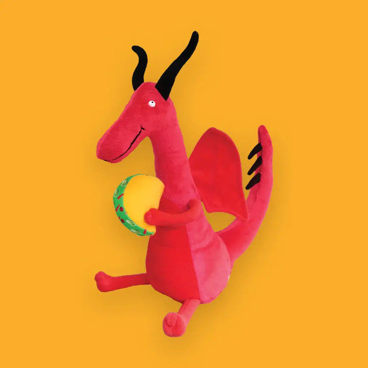 Red dragon plush toy with black horns and a green ring on a yellow background