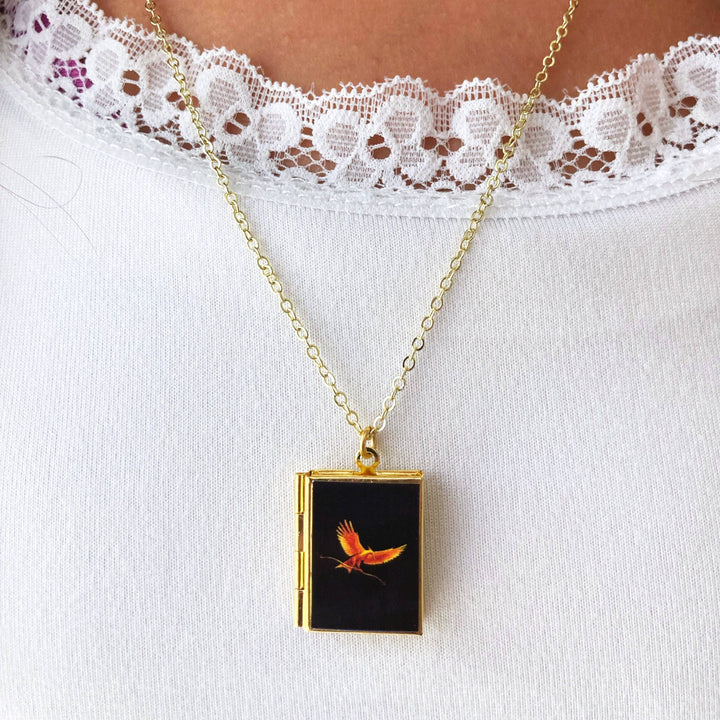 Necklace with a pendant featuring an orange bird design on a white lace garment.