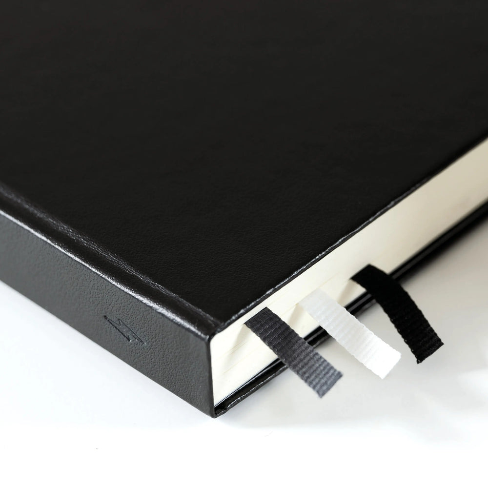 Black notebook with a white page on a light gray background