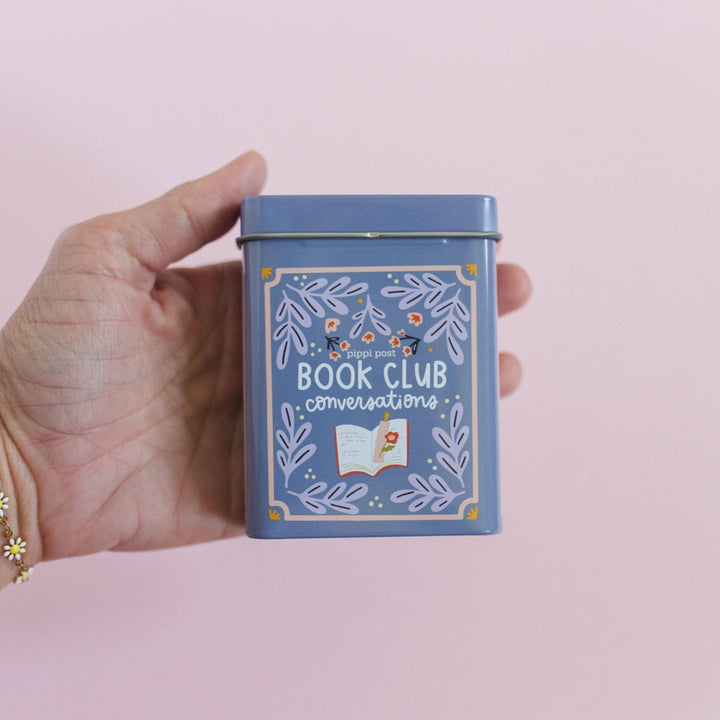 Hand holding a blue tin with &