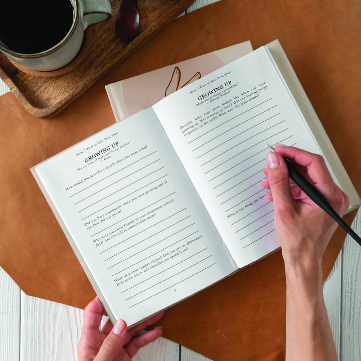 Person holding a notebook with writing on a wooden table next to a cup of coffee.