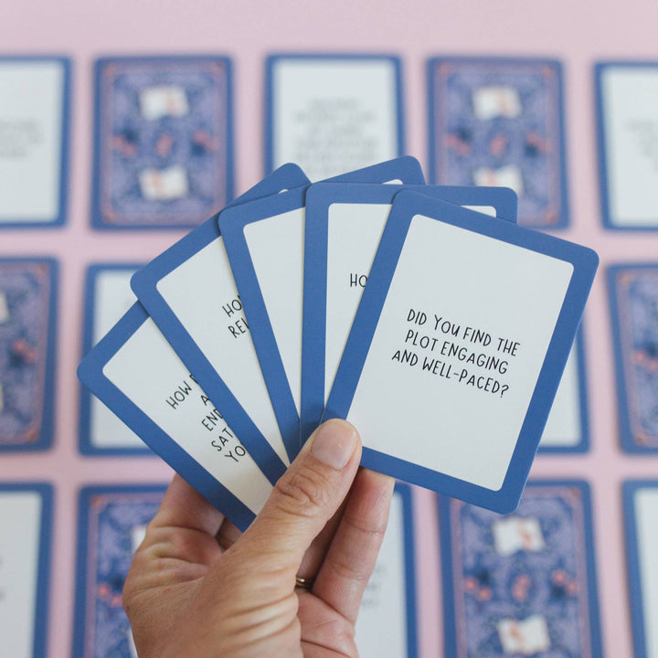 Hand holding a set of question cards with text against a pink background with similar cards.