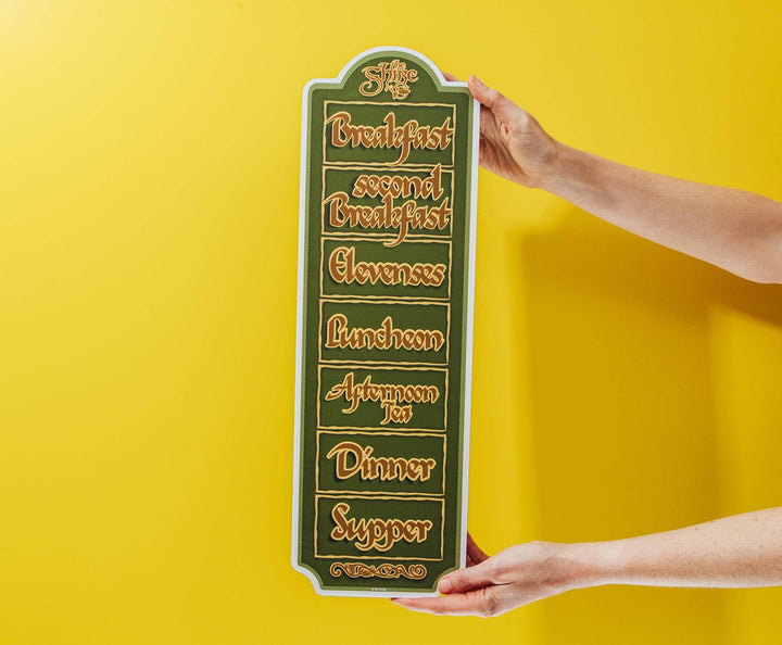 Person holding a decorative sign with meal times on a yellow background