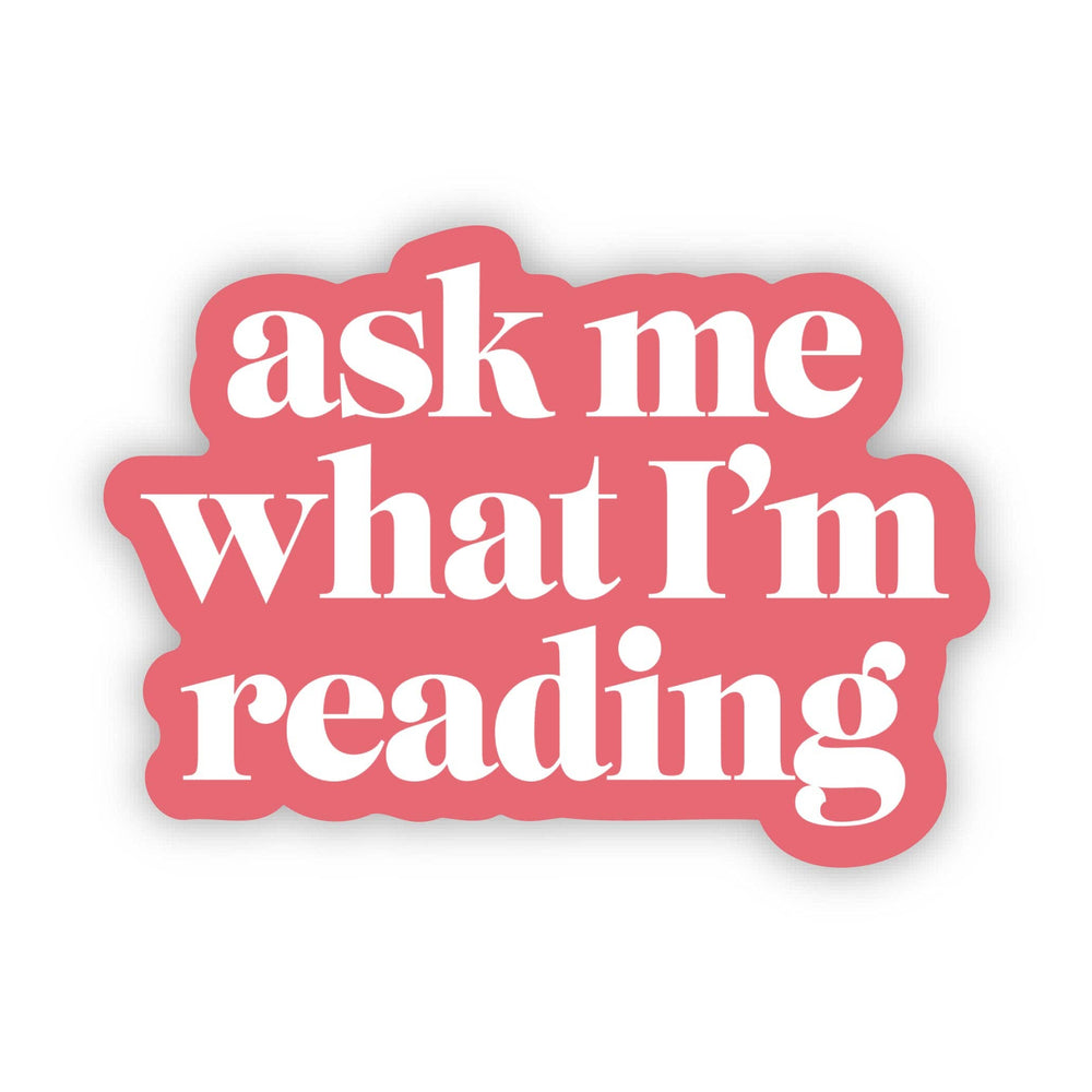 Pink sticker with white text 'ask me what I'm reading' on a white background
