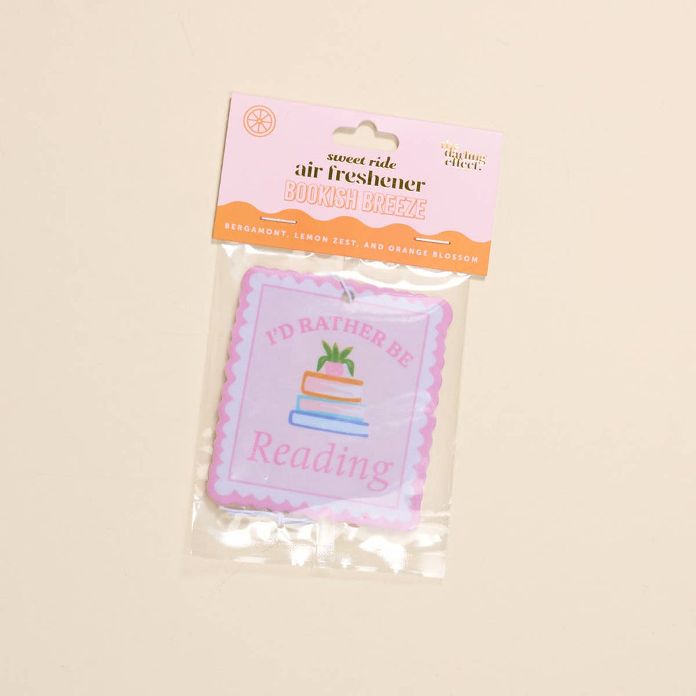 Air freshener with 'I'd Rather Be Reading' text and cake illustration in packaging on a beige background