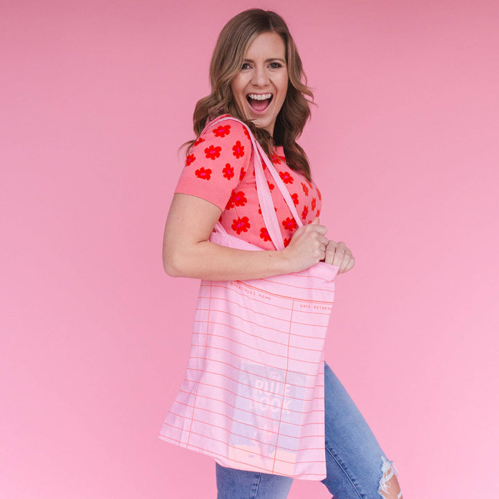 Woman wearing a pink floral top and pink bag against a pink background